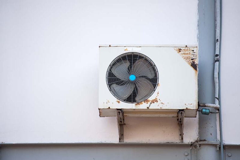 A rusty air conditioner mounted in a wall | Repair Replace Air Conditioner | 3 Telltale Signs It’s Time for a New AC | Olympia, WA