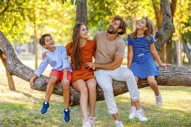 Image of family sitting on tree. 4 Factors to Consider When Buying a Heat Pump.